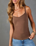 Women's brown ruched tank top with V-neckline, paired with blue jeans and gold jewelry, modeled on gray background