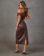 Woman in brown satin asymmetric off-shoulder top and chocolate faux leather midi skirt with side slit, gold cuff and strappy heels