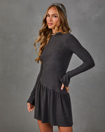 Woman in a charcoal gray long sleeve drop waist mini dress with flared cuffs and a herringbone headband, hand on hip