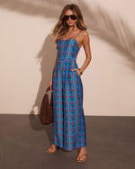 Blue floral stripe maxi dress with spaghetti straps, worn with tan sandals and woven bag, summer resort style