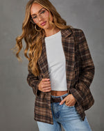 Woman wearing a brown plaid double-breasted blazer over a white cropped tee, light wash jeans, brown belt and clear-frame glasses