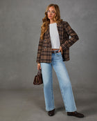 Woman wearing a brown plaid double-breasted blazer, white tee, light wash wide-leg jeans, and brown loafers with a mini handbag