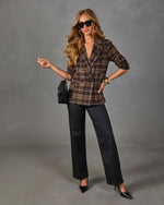 Woman in brown plaid double-breasted blazer, black wide-leg coated pants, black pointed heels, and quilted chain crossbody bag