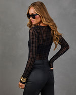 Woman in black sheer plaid flocked mesh long-sleeve bodysuit with coated black jeans, gold cuff bracelets and square sunglasses