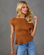 Woman wearing rust brown ribbed knit short-sleeve sweater top with blue jeans, styled with gold hoop earrings and bracelets