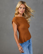 Woman wearing rust brown ribbed knit short sleeve sweater top with blue jeans, gold earrings and bracelet