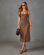 Woman wearing brown midi slip dress with spaghetti straps, styled with gold jewelry, dark sunglasses, and black heeled sandals