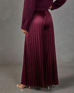 Burgundy satin pleated wide-leg pants with a matching knit sweater and nude heeled sandals, back view