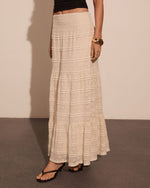 Cream lace tiered maxi skirt with smocked waist, paired with black crop top and strappy heeled sandals