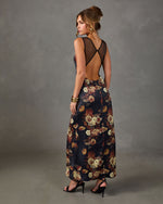 Floral satin maxi dress with sheer mesh open back and cross-strap detail, styled with black block-heel sandals and gold cuff