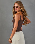 Woman wearing brown ribbed knit tank top and cream corduroy pants with tortoiseshell sunglasses and gold jewelry