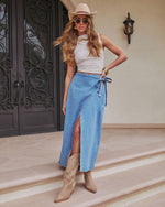 A woman wearing the Maebelle Wrap Tie Denim Maxi Skirt paired with boots.