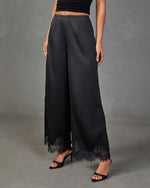 Black satin wide-leg palazzo pants with lace trim hem, styled with black heels and crop top
