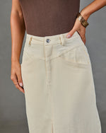 Cream corduroy midi skirt with angled pockets and silver button closure, paired with brown ribbed bodysuit