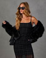Woman in black plaid mesh midi dress with black faux fur coat, square sunglasses and quilted black chain shoulder bag
