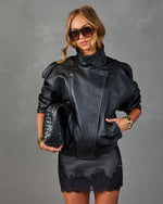 Woman in black leather moto jacket, lace mini skirt, aviator sunglasses, holding woven clutch, gold cuff bracelets