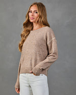 Women's tan knit oversized sweater with contrast stitching detail, paired with white jeans, casual fall style