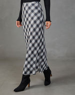 Navy plaid satin bias-cut maxi skirt styled with black ribbed long-sleeve top and black heeled ankle boots