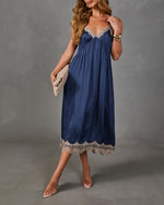 Navy satin midi slip dress with beige lace trim at the V-neckline and hem, styled with clear heels and a woven clutch