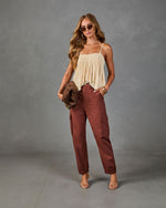 Woman wearing cream smocked camisole top and rust brown cargo jogger pants with strappy heels and gold accessories