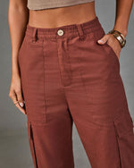 Rust brown linen cargo pants with elastic waistband, wooden button, and side pockets on woman