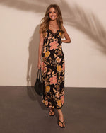Black floral maxi slip dress with lace trim neckline, pink and gold flowers, styled with black sandals and woven bag