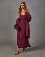 Woman in a burgundy lace-trimmed satin slip maxi dress with an oversized knit cardigan, mini bag and strappy heeled sandals