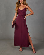 Burgundy satin midi slip dress with lace trim and side slit, styled with matching clutch, strappy sandals and gold bracelets