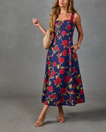 Navy floral midi dress with red roses, square neckline, A-line silhouette, styled with nude strappy heels and woven bag