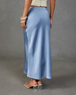 Blue satin maxi slip skirt with A-line silhouette, styled with cream ruched crop top and clear block heel mules