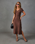 Brown satin midi dress with short sleeves and black trim on model, styled with black strappy sandals and woven bag