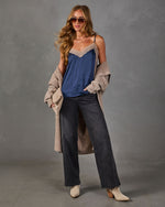 Woman wearing a navy satin lace-trim cami, oatmeal knit cardigan, black wide-leg jeans and cream pointed western ankle boots
