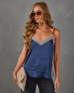 Navy satin cami top with beige lace trim, styled with black jeans, aviator sunglasses, gold necklaces and a woven clutch
