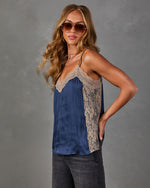 Navy satin cami top with tan lace trim and V-neckline, styled with gray denim and aviator sunglasses