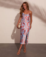 Light blue tropical floral print satin slip midi dress with cowl neck, side slit, and spaghetti straps on smiling model
