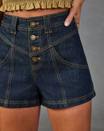 Dark wash high-waist denim shorts with four antique brass buttons, contrast gold stitching, and diagonal pocket seams