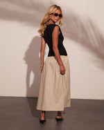 Woman wearing black fitted sleeveless top and beige midi skirt with black kitten heel sandals and sunglasses, back view