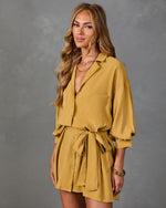 Woman wearing mustard yellow button-down mini shirt dress with tie waist, puff sleeves, and chest pocket, styled with gold jewelry