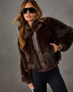 Woman wearing a brown faux fur bomber jacket with leather trim and gold zipper, styled with aviator sunglasses and gold bangles