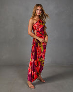 Floral pleated one-shoulder maxi dress in red and purple with cutout waist, styled with nude strappy heels