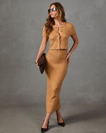 A woman models a matching tan knit two-piece set consisting of a short-sleeve cropped top with buttons and a high-waisted pencil skirt, styled with dark brown heels and a dark brown clutch against a gray studio background.