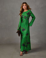 Green satin maxi dress with long sleeves, dark floral print and bias-cut skirt, styled with strappy heels and brown clutch