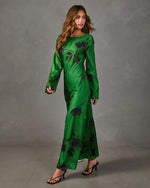 Green satin floral maxi dress with long flared sleeves and bias-cut skirt, styled with brown strappy heeled sandals
