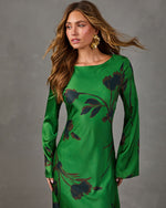 Green satin floral maxi dress with bell sleeves and boat neckline, styled with gold statement earrings