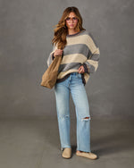 Woman in oversized gray and cream striped sweater, light-wash ripped wide-leg jeans, tan suede tote and suede clogs