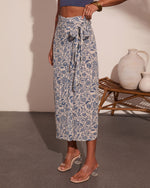 Woman wearing cream and blue floral midi skirt with tie waist, paired with blue crop top and clear block heel sandals