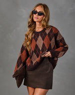 A woman modeling a brown and rust argyle knit sweater with a dark brown mini skirt, styled with black sunglasses, against a textured gray studio background.