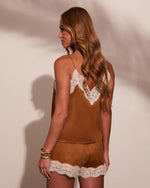 Woman wearing brown velvet lace-trim camisole and matching shorts set, back view, warm studio lighting