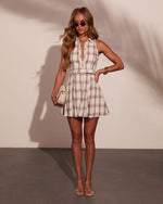 Woman wearing cream plaid belted mini shirt dress with clear heeled sandals, gold accessories, and small cream handbag