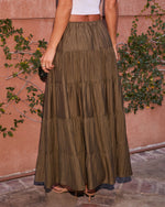 Olive green tiered maxi skirt with elastic waist, paired with white crop top and strappy heels, outdoor boho style